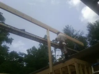 Carpenter setting a ridge beam over a new addition frame — Ice Dam Removal by Roofing Brothers in Langston