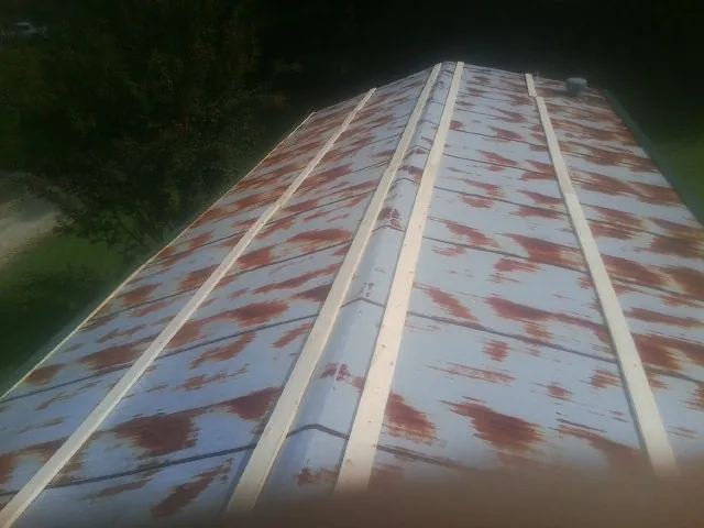 Rusted metal roof panels with new wood purlins before replacement — Storm Damage Roof Repair in Langston by Roofing Brothers