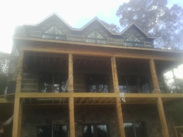 Dormers and porch framing on a large log home under construction — Roof Coating work by our crew in Langston