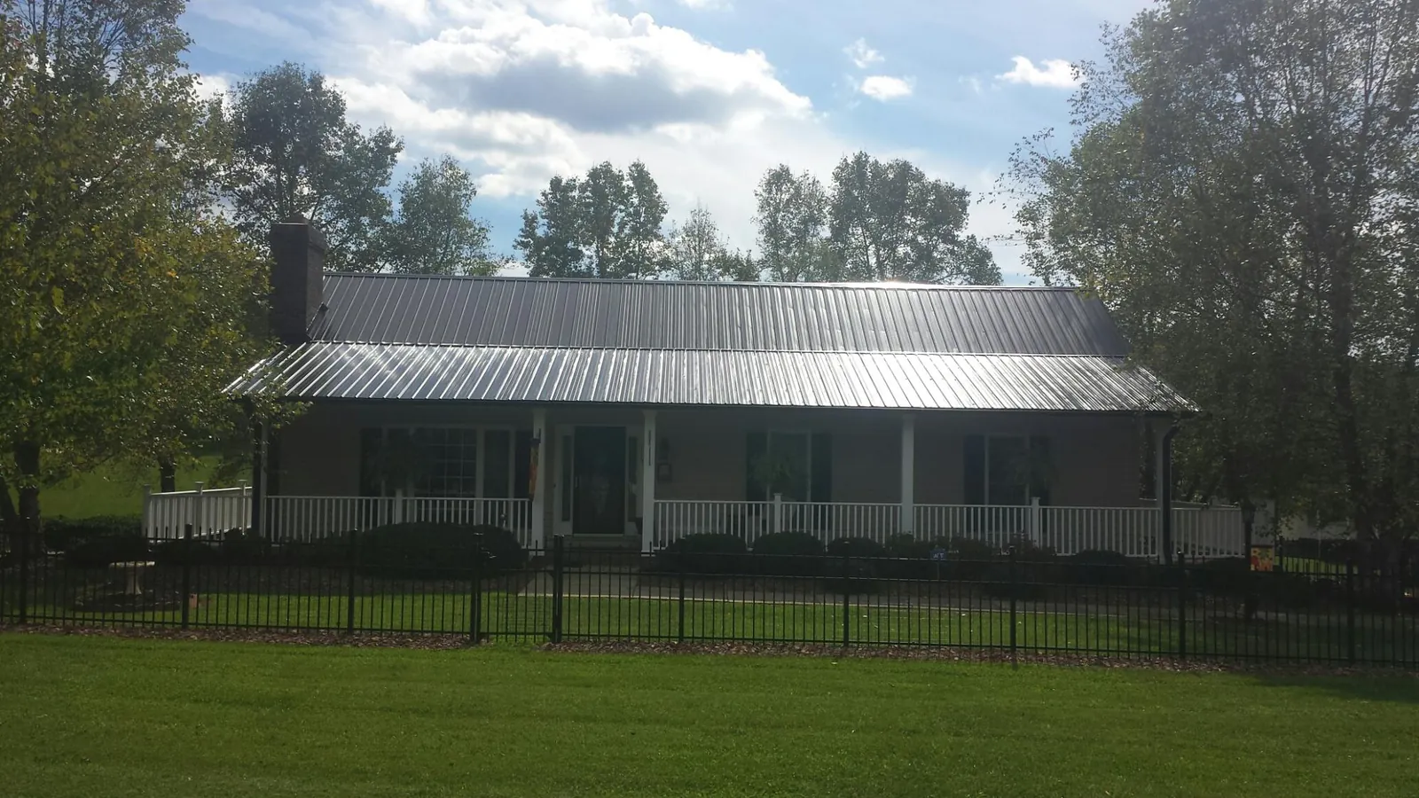 Gray metal roof on a brick ranch with a full width front porch — Gutter Guard Installation work by our crew in Langston