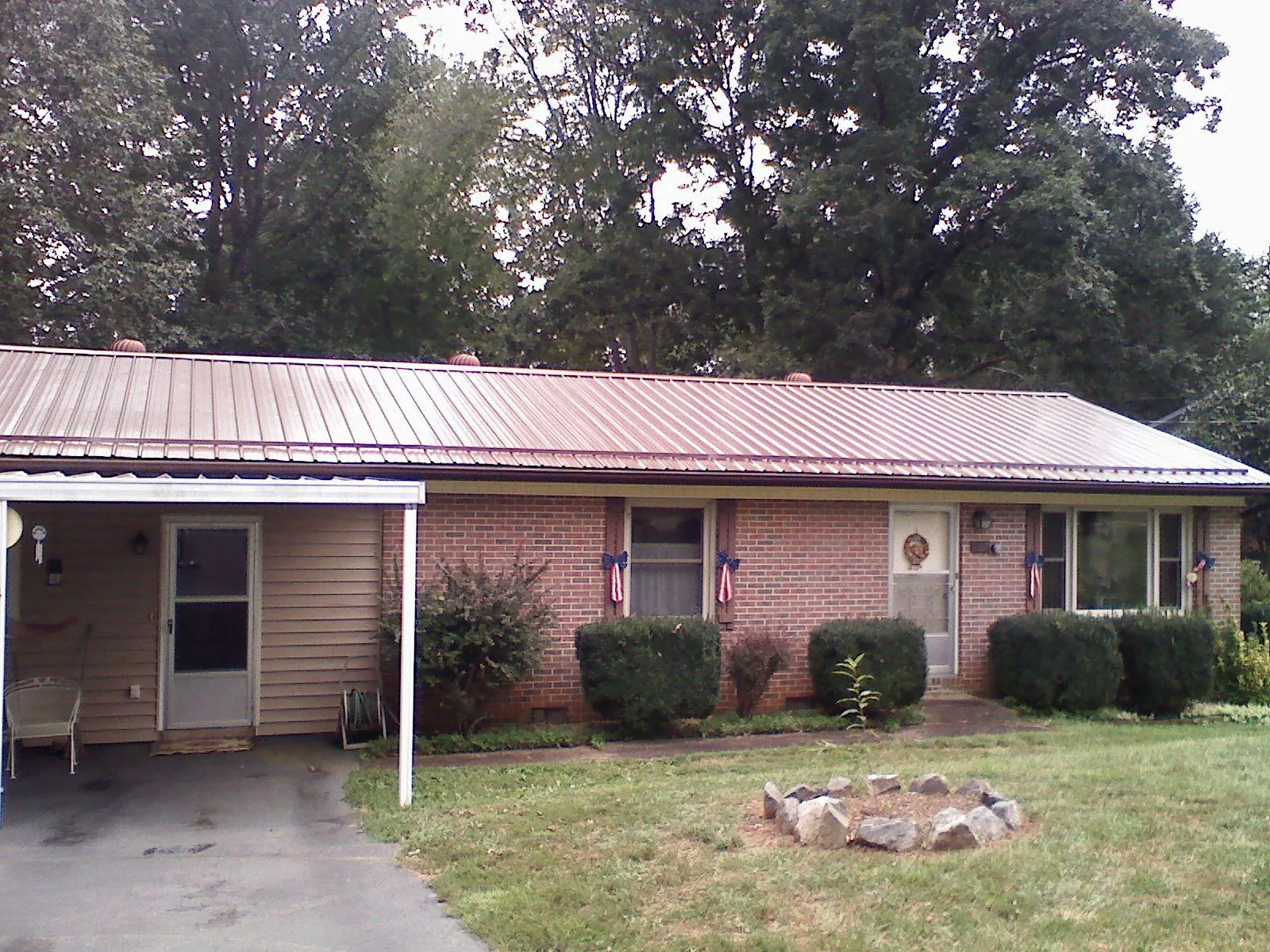 Bronze metal roof and carport on a brick ranch home — Roof Repair work by our crew in Langston