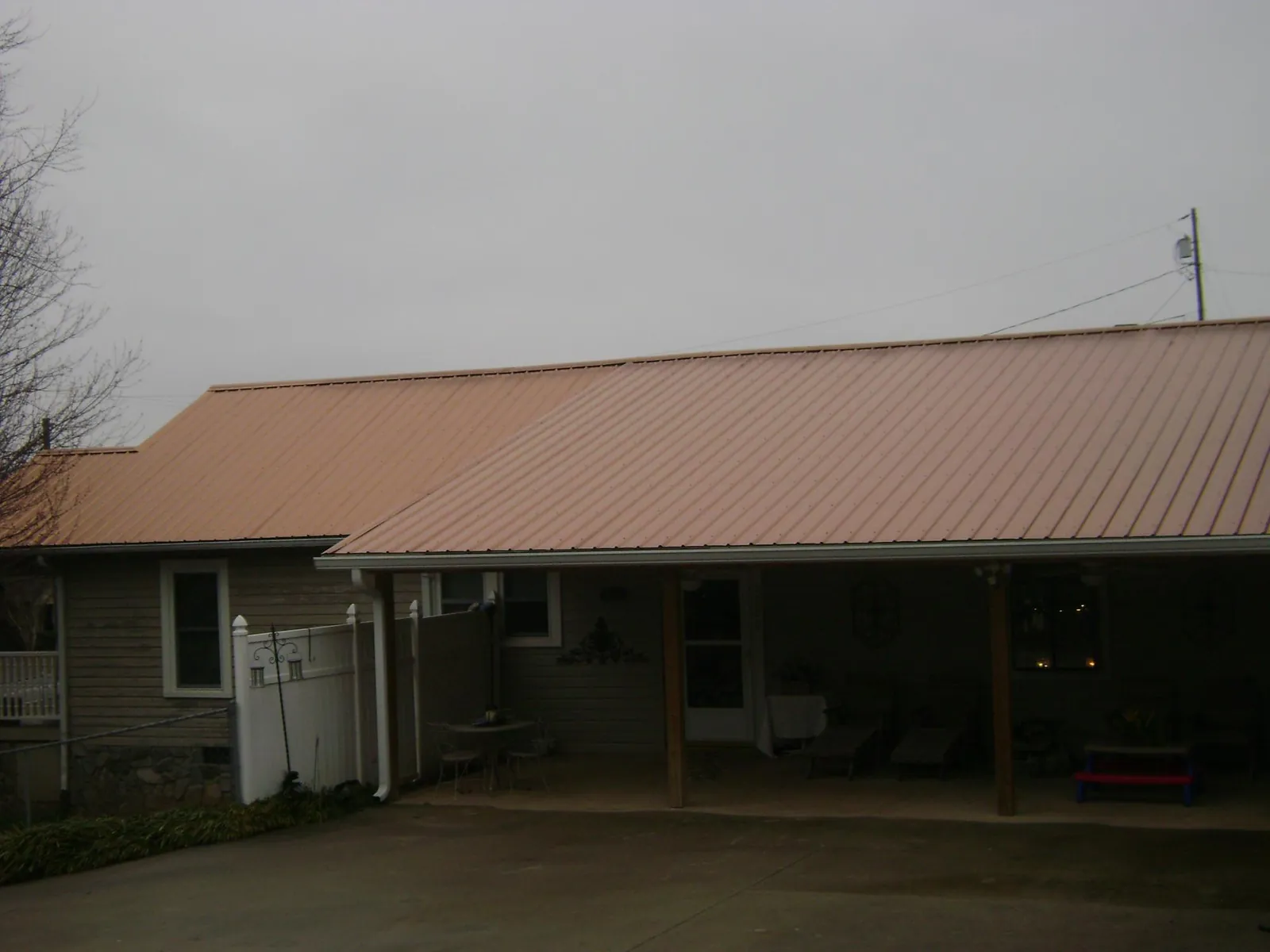 Copper toned metal roof over a wide covered patio in Langston