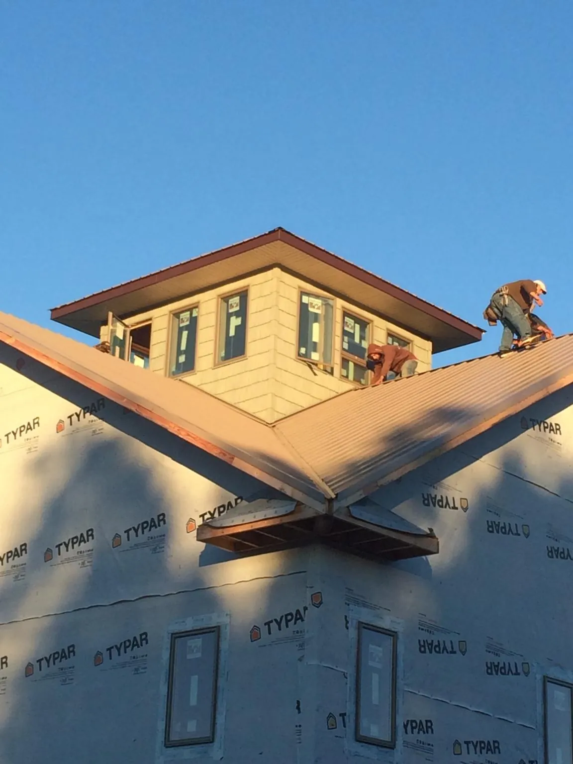 Roofers working around a rooftop cupola on a new metal roof at sunset — Roof Waterproofing in Langston by Roofing Brothers